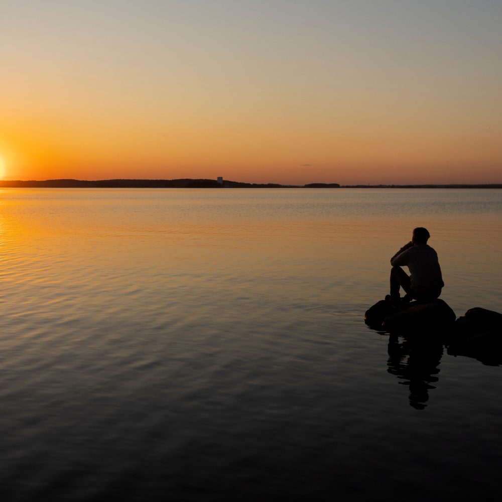 "Golden hour sunset over calm water with a silhouette in stillness — Soft Frequencies™ frequencywear™ blog on harmony at 432 Hz.