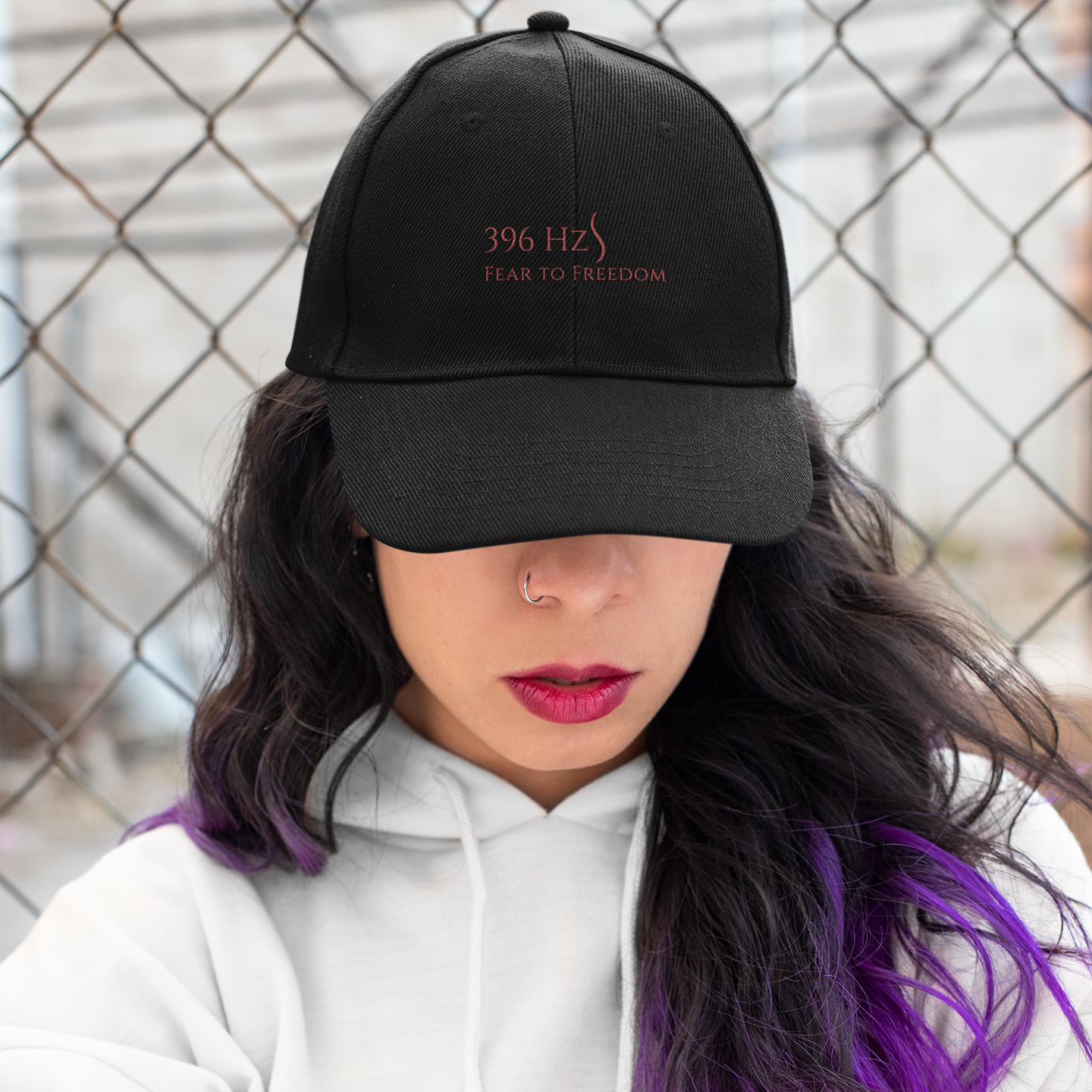 Woman wearing 396 Hz Fear to Freedom black hat – spiritual frequencywear™ hat styled with hoodie, bold lips, and purple hair