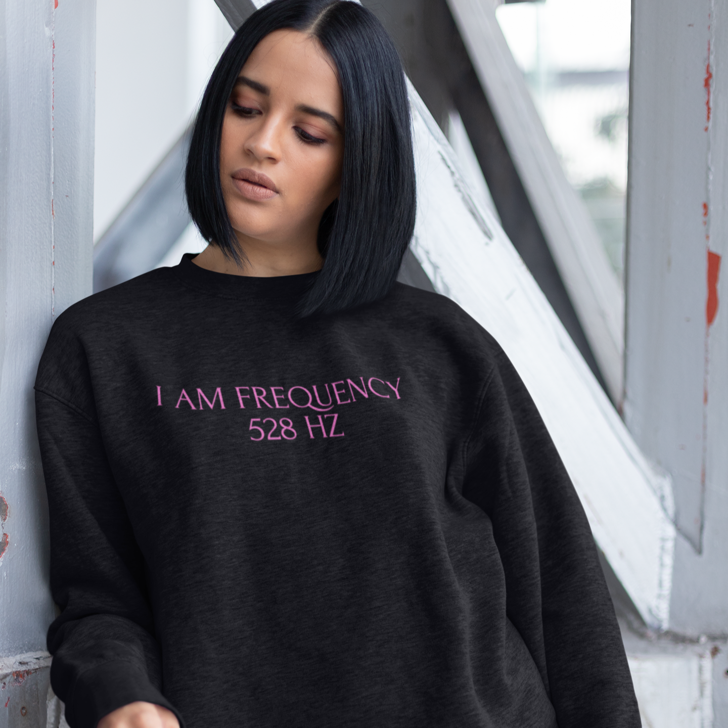 Person wearing a black sweatshirt with 'I AM FREQUENCY 528 Hz' text in pink.