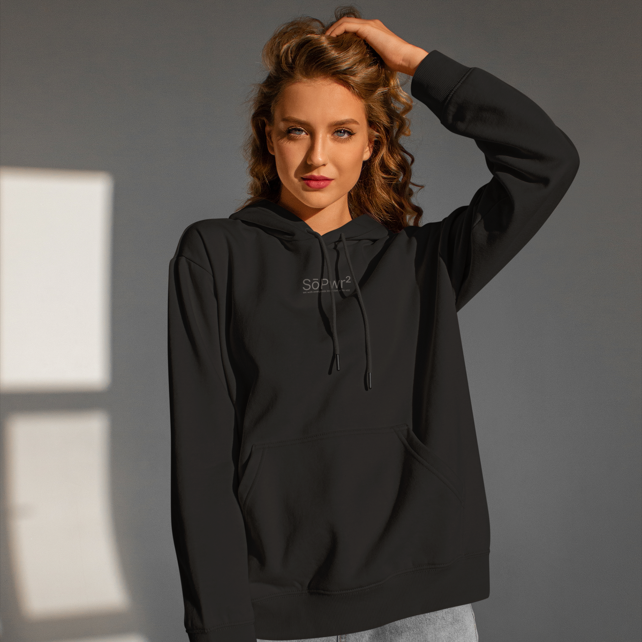 Woman wearing a black hoodie with a Sopwer2 logo against a gray background