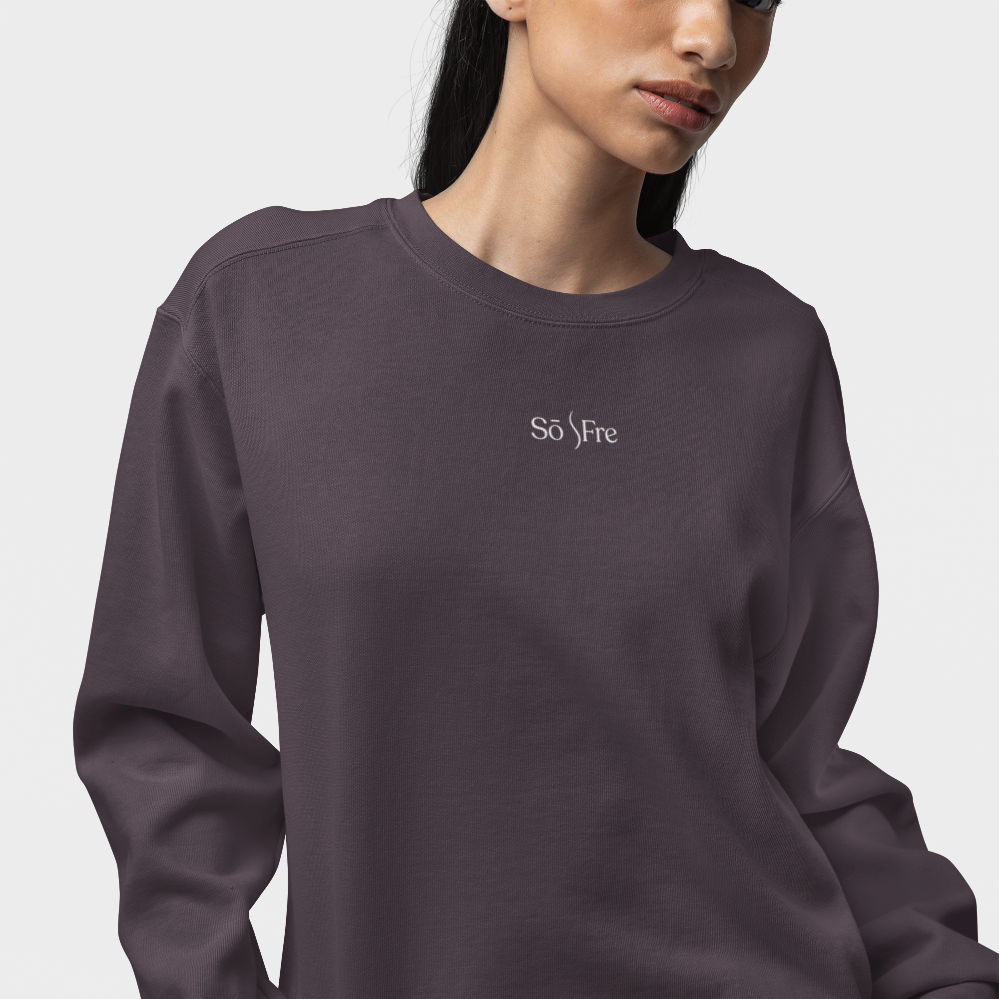 Woman wearing dark plum frequencywear crewneck with “SōFre” embroidery — minimalist spiritual fashion for softness and strength